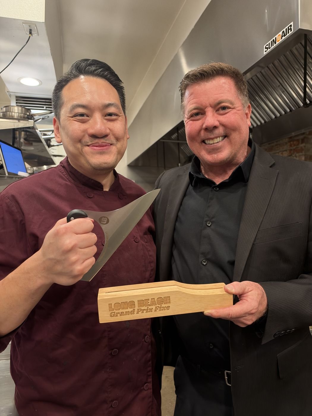 Executive Chef Danny Le and the Proprietor of Chez Bacchus holding the 2026 Long Beach Grand Prix Fixe trophy in the kitchen
