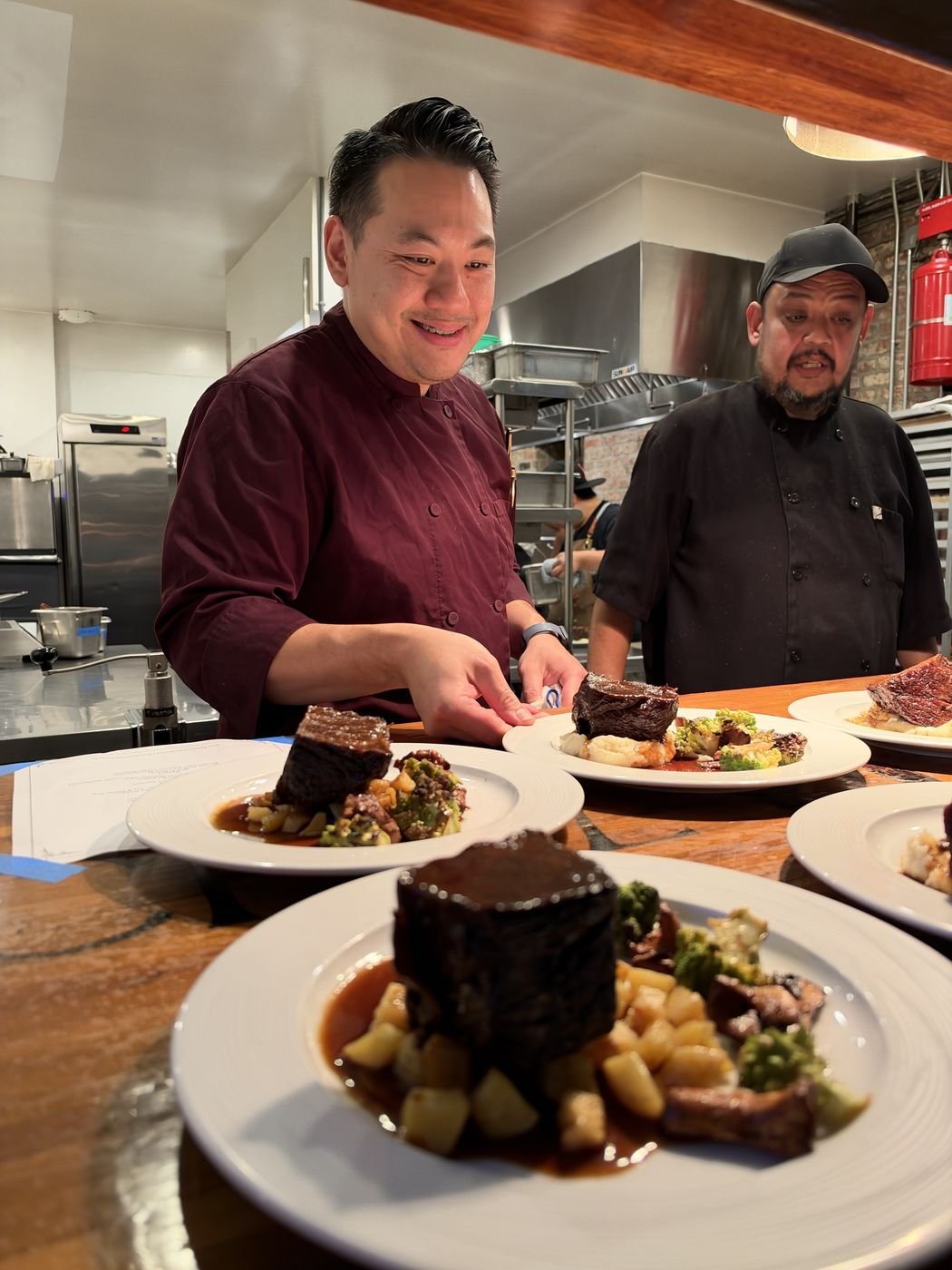 Chef Danny Le and a member of the kitchen team plating dishes together at the pass