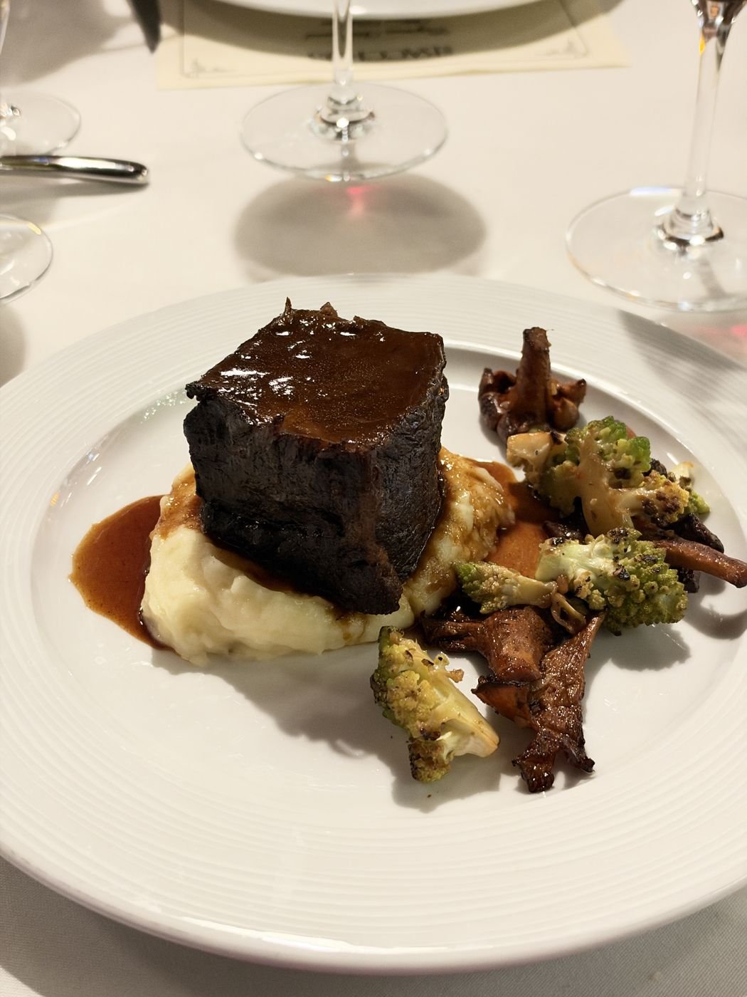 A plated course and a glass of red wine on a white tablecloth in the Chez Bacchus dining room